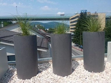 Sklolaminátové kvetináče v RAL farbe s vysokými okrasnými trávami na streche